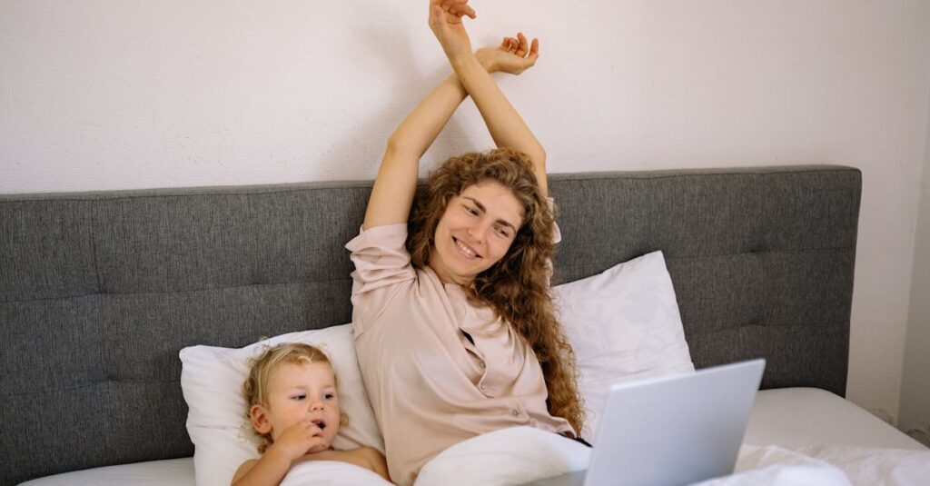 Mother and child enjoying a cozy morning, smiling and bonding over a laptop in bed.