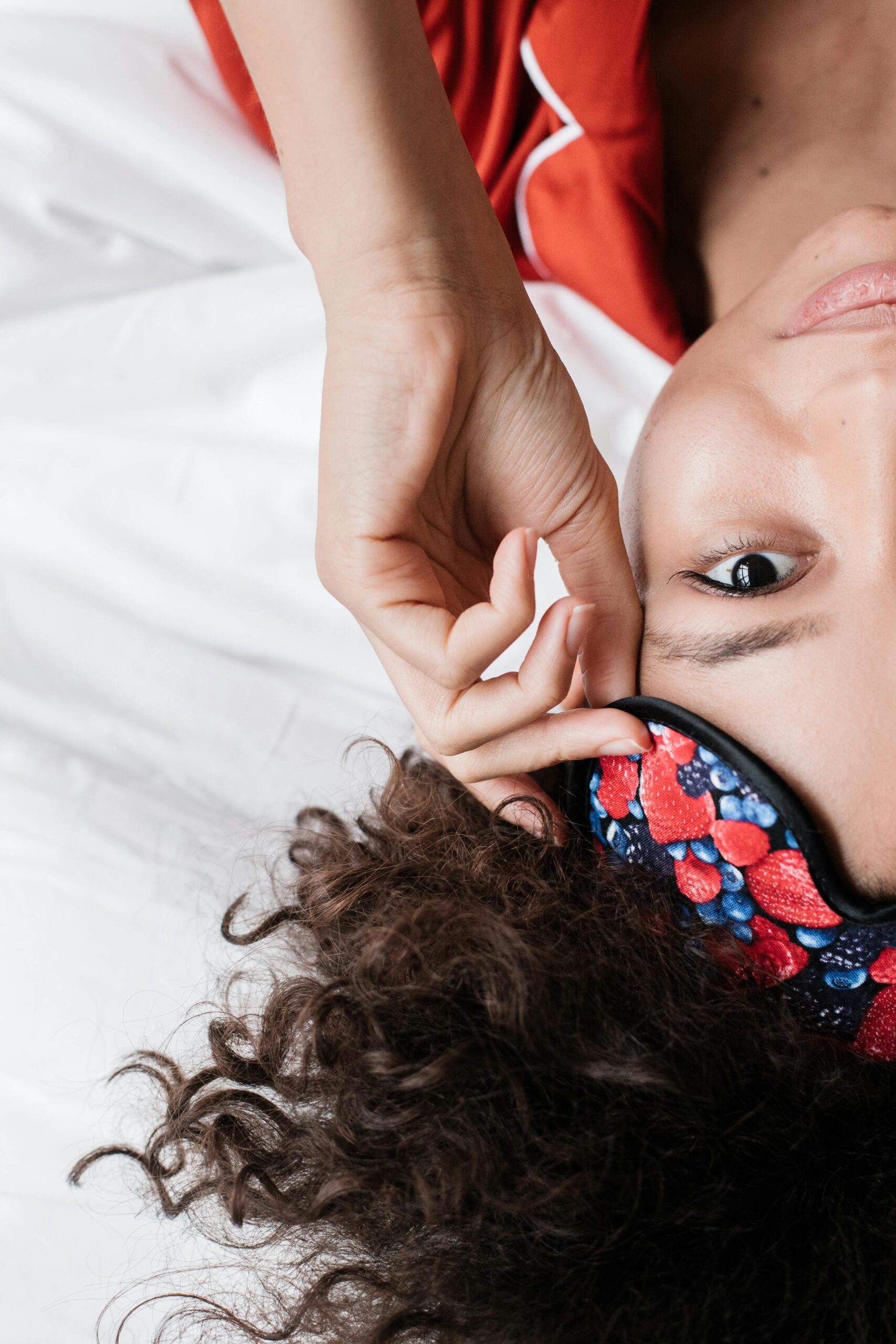 Close-up of a woman in bed with a colorful sleep mask, showcasing relaxation and comfort.